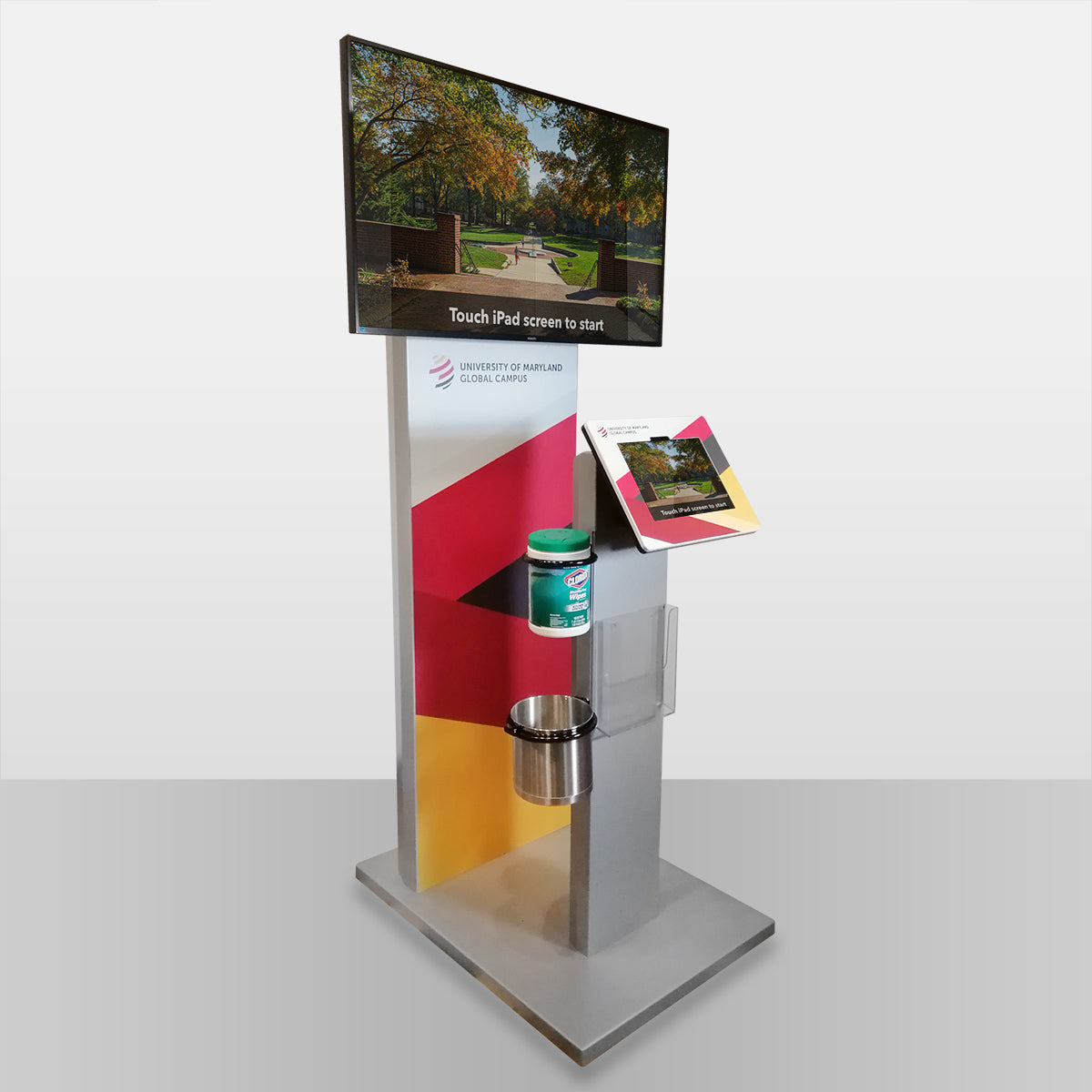 A freestanding tablet kiosk with an external monitor attachment. The tablet screen is mirrored to the external screen for high visibility.